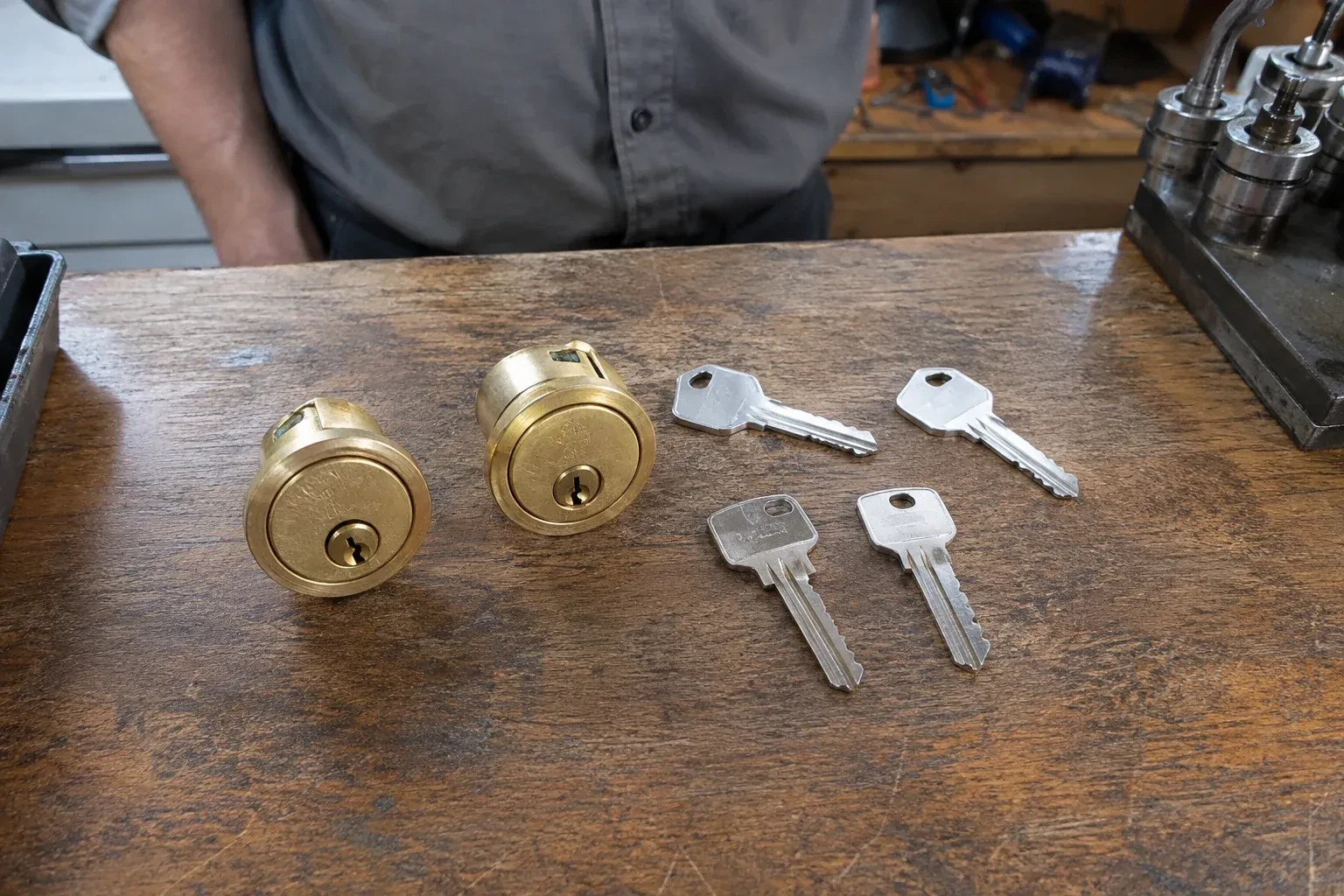 Two detached brass lock cylinders and four house keys on a wooden counter. — Lock Rekeying, Vaughan